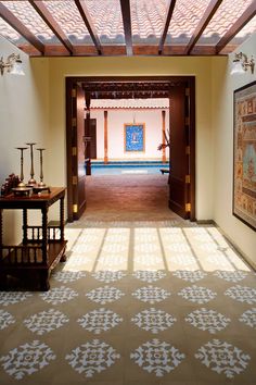 a hallway leading to an indoor swimming pool with tiled flooring and wooden framed artwork on the walls