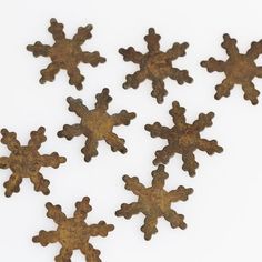 six rusted metal snowflakes on a white surface