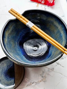 two chopsticks sticking out of a blue bowl