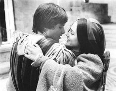 a young boy and girl embracing each other on a bench in front of a building