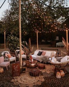 an outdoor seating area is decorated with lights and wicker furniture, including two sofas