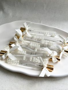 white and gold wedding garters are arranged on a platter with ribbon bows