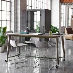 a table with two chairs and a laptop on it in an open room next to a couch