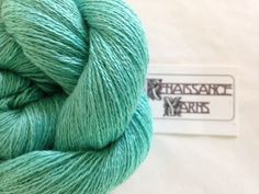 a skein of green yarn sitting on top of a white table next to a tag