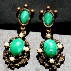 "These earrings are amazing - very ornate and beautifully crafted.  Even the back is amazing. There are 2 green stones which are quite marbleized so I can't identify them.  Definitely not malachite. I also don't know if the pearls are real -hard to tell. They are quite heavy so they would not convert to pierced earrings They measure 2\" from top to bottom Thank you for looking" Green Metal Drop Clip-on Earrings, Green Metal Clip-on Earrings, Vintage Green Cabochon Earrings, Vintage Style Emerald Drop Earrings, Elegant Green Nickel-free Clip-on Earrings, Vintage Green Jade Earrings, Green Cabochon Costume Jewelry, Green Clip-on Metal Earrings, Oval Green Clip-on Earrings