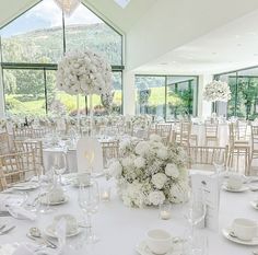 a table set up with white flowers and place settings