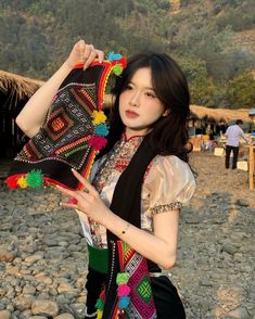 a woman is standing on the beach with her scarf around her neck