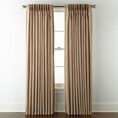 an open window with beige curtains and wood floors