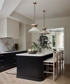 a large kitchen with an island in the middle and two pendant lights hanging from the ceiling