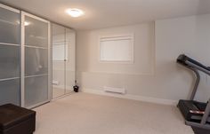 an empty room with a treadmill, exercise machine and glass closet doors in it