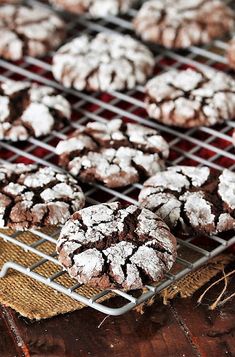 chocolate crinkle cookies cooling on a wire rack, with powdered sugar sprinkled on top