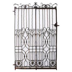 an iron gate with wrought bars and scrolls on the top, against a white background