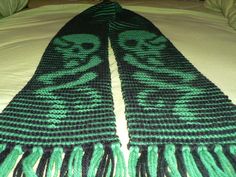 a green and black scarf laying on top of a bed