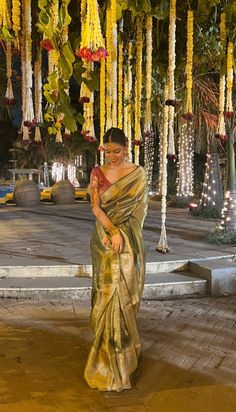 a woman in a sari standing under some flowers