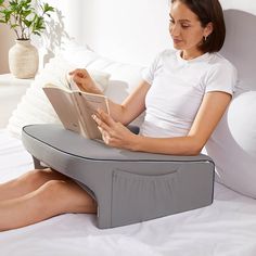 a woman sitting on a bed reading a book