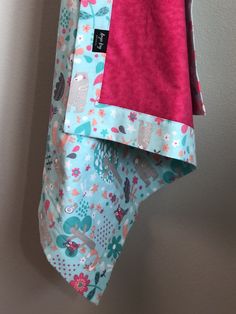 two pieces of clothing hanging on a clothesline with pink and blue fabric in the background