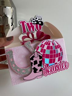 a pair of pink cowboy boots sitting on top of a paper bag with the word two in it