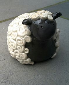 a black and white sheep statue sitting on the sidewalk