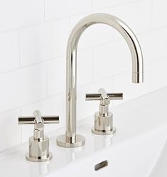 two chrome faucets sitting on top of a white sink