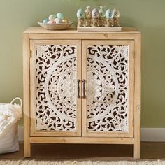 a wooden cabinet with ornate carvings on the doors and drawers is shown in front of a green wall