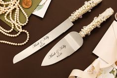 two personalized wedding knives next to pearls and other items on a table with ribbons