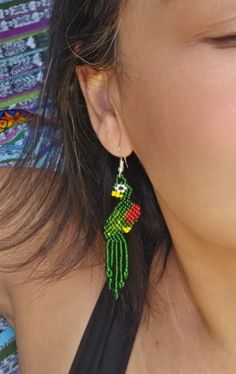 Expertly crafted with intricate beadwork, these Large Beaded Quetzal Earrings embody the beauty and culture of Guatemala. The dainty green and red design adds a stunning touch to any outfit, making them a unique and elegant accessory for any occasion. Embrace the unparalleled craftsmanship and representation of Guatemalan culture with these stylish earrings. Measurements: 3 inches long 0.50 inches wide Green Bohemian Beaded Earrings With Tiny Beads, Traditional Green Beaded Jewelry, Bohemian Green Dangle Beads, Green Bohemian Dangle Beads, Unique Handwoven Green Earrings, Bohemian Green Beaded Earrings With Colorful Beads, Handwoven Green Jewelry For Festival, Adjustable Green Bohemian Beaded Earrings, Green Handwoven Jewelry For Festival