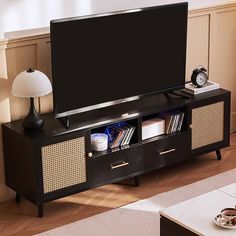 a flat screen tv sitting on top of a wooden entertainment center next to a lamp