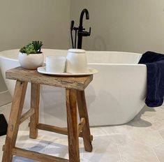 a white bath tub sitting next to a wooden stool