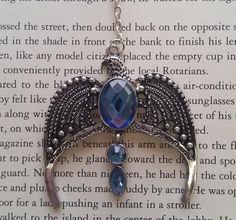 a necklace with an angel wing and blue crystal stones hanging from it's side