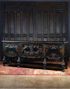 an ornately carved wooden dresser in front of a blue wall and rug on the floor