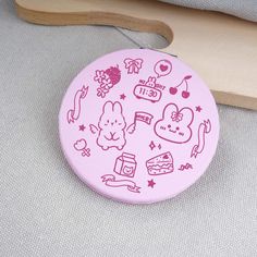 a pink brooch with various stickers on it sitting next to a wooden object