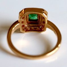 Associated with Venus, Roman goddess of love, the power of emeralds runs deep. Here 0.33 carats of diamond surrounds a central emerald in a 14k open-back setting. Sizes 5-8. Green Emerald Ring With Halo Style Fine Jewelry, Green Emerald Halo Diamond Ring, May Birthstone Ring With Emerald Cut And Halo Setting, 14k Gold Emerald Ring With Halo Design, Gold Halo Emerald-cut Emerald Ring, Formal 14k Gold Emerald Ring With Halo, Emerald Halo Ring In Yellow Gold, Formal Green Halo Cluster Ring, 14k Gold Birthstone Ring With Emerald Cut Halo Setting