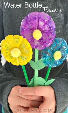 three plastic flowers sitting on top of each other in front of a person's hands