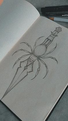 an open book with a pencil drawing of a spider on it's cover and two pens next to it