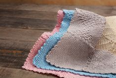 three knitted dishcloths sitting on top of a wooden table