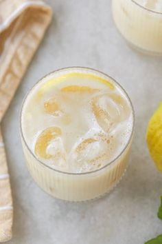 two glasses filled with lemonade and ice on top of a table