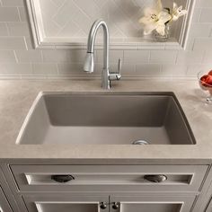 a kitchen sink sitting under a faucet next to a vase with flowers in it