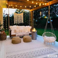 an outdoor living area with white furniture and string lights