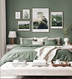 a bedroom with green walls and pictures on the wall above the bed in front of it