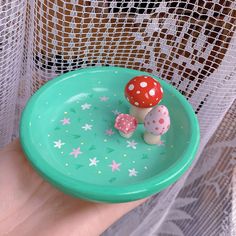 a hand holding a green plate with two small mushrooms on it and stars around the edge