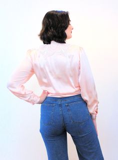 "This is a sweet vintage 80s lace collar blouse! It's made of shimmery blush pink-peach satin, very lustrous, with modest pleating in the front, puffed shoulders with shoulder pads, and long sleeves with single button cuffs. It has a very pretty, large white cut lace collar, a round neckline, and it closes with six white pearl buttons in a hidden front placket, plus a snap at the throat. The blouse is in very good clean vintage condition, no flaws noted. The label says \"Nicola, 100% Polyester, Pink Long Sleeve Blouse With Lace Collar, Feminine Fitted Peach Blouse, Fitted Feminine Peach Blouse, Chic Pink Blouse With Lace Trim, Fitted Pink Blouse With Lace Collar, Feminine Long Sleeve Peach Blouse, Feminine Peach Long Sleeve Blouse, Feminine Pink Blouse With Lace Top, Chic Pink Blouse With Lace Collar