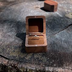 a wooden ring box sitting on top of a tree stump