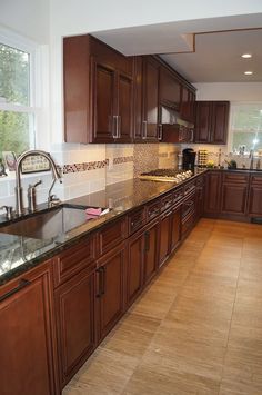 a large kitchen with wooden cabinets and marble counter tops, along with dark wood flooring