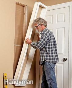 a man standing in front of a white door with a ladder next to him and looking at the wall