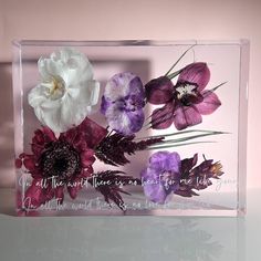 there is a glass block with flowers in it on the table and an inscription below