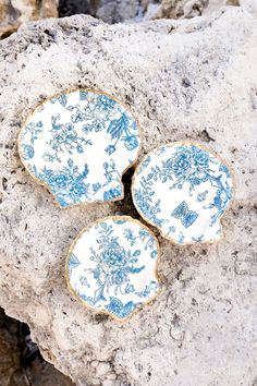 three blue and white plates sitting on top of a rock