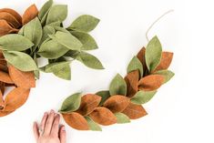 someone is making a wreath out of felt leaves and twine with scissors on the table