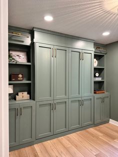 an empty room with green cabinets and wood floors