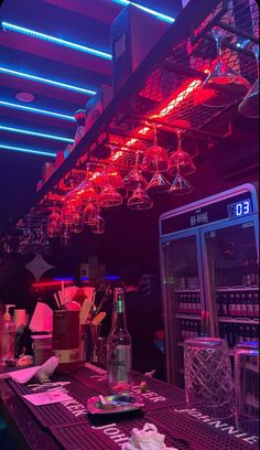 a bar with many wine glasses hanging from the ceiling and bottles on the counter in front of it