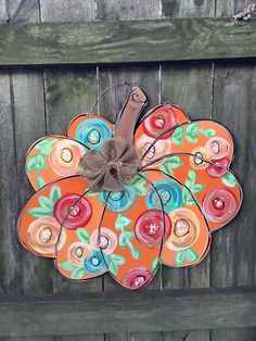 an orange decorative pumpkin hanging on a wooden fence